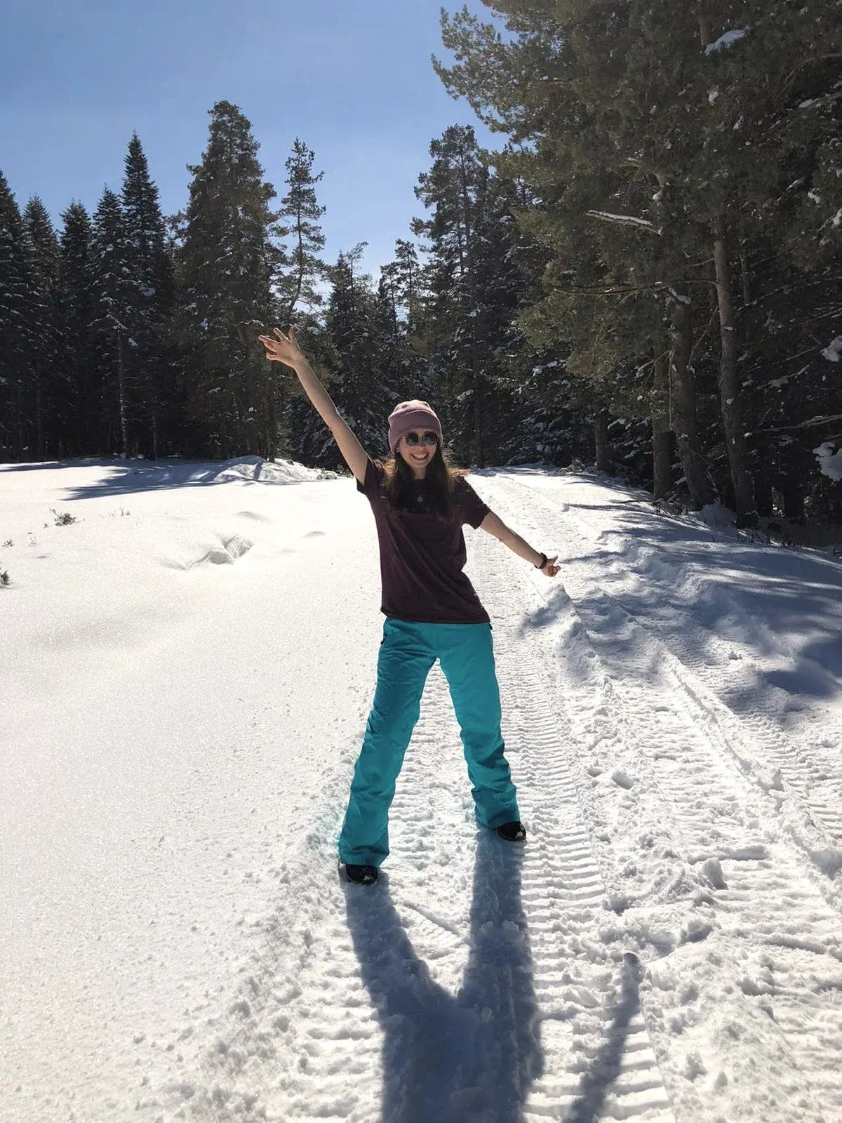 Ece with her arms raised on a snowy forest road