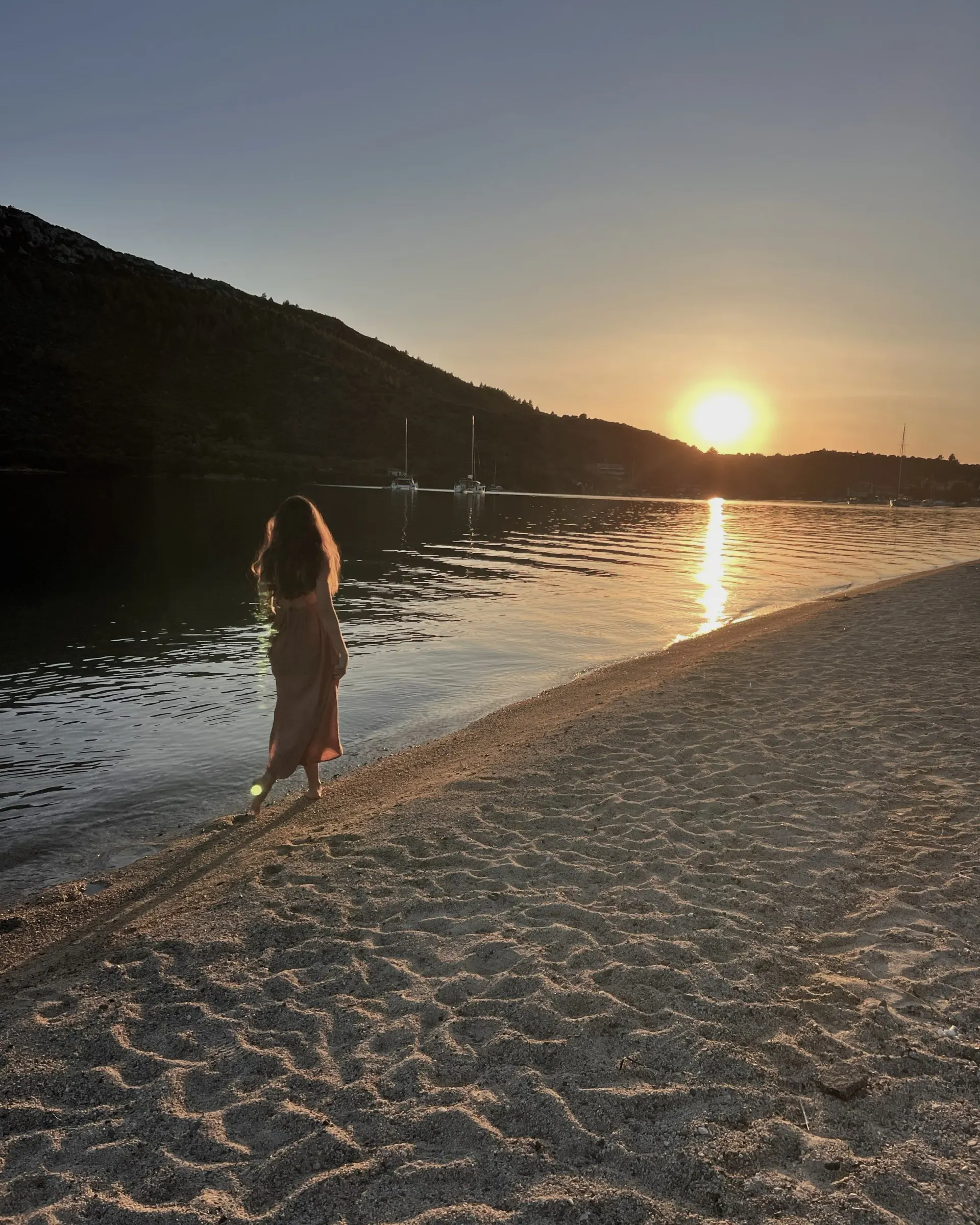 Ece at the water's edge as the sun sets behind the hills