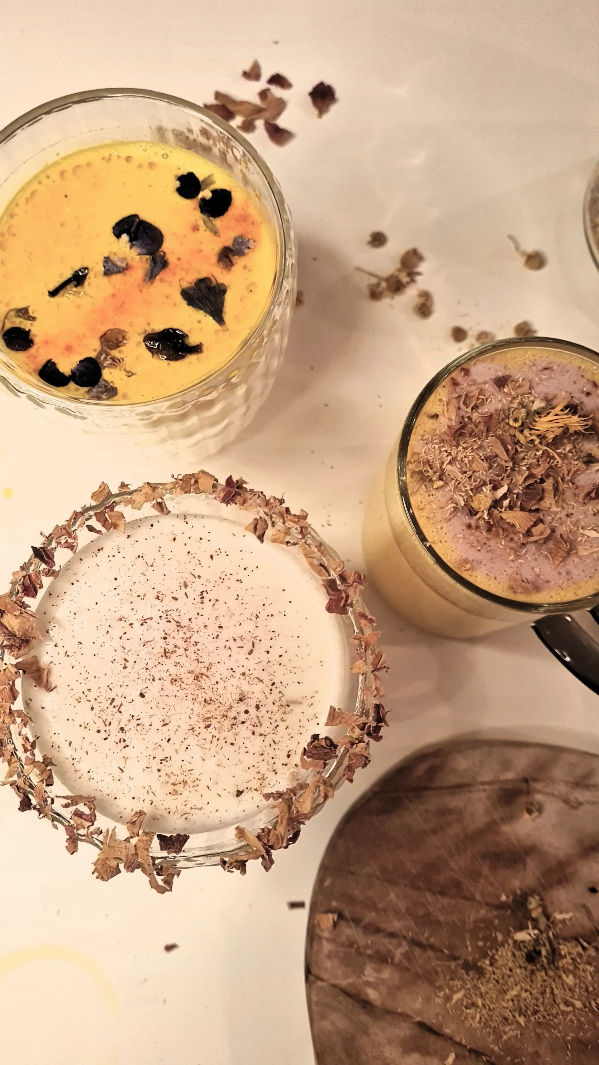 Golden milk drinks topped with edible flowers and spices, seen from above