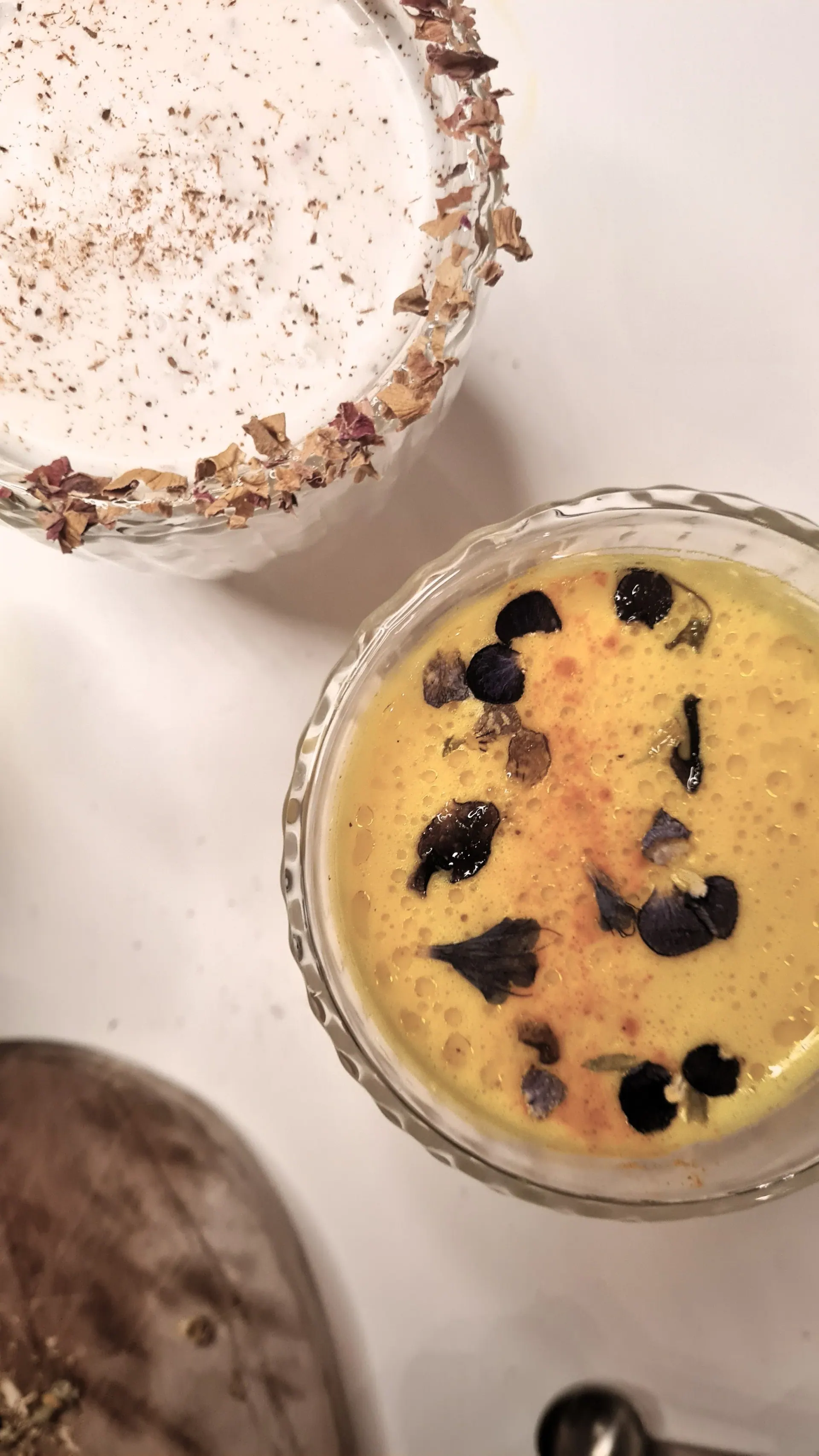 Two glasses of golden milk decorated with flowers and spices